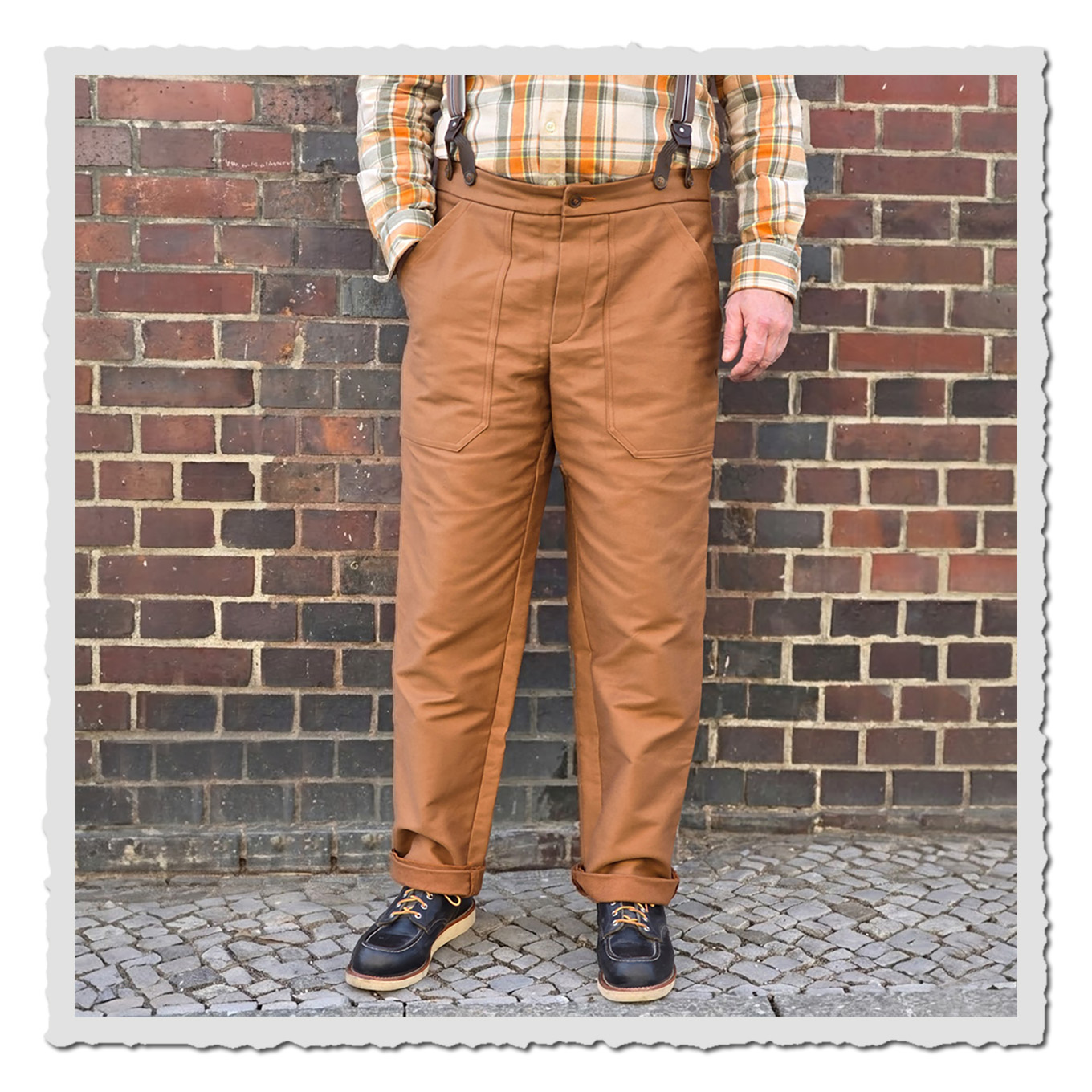 Frontansicht der Arbeiterhose vor Ziegelwand: aufgesetzte Taschen mit viel Platz, robust verarbeitet, Canvas entenbraun.